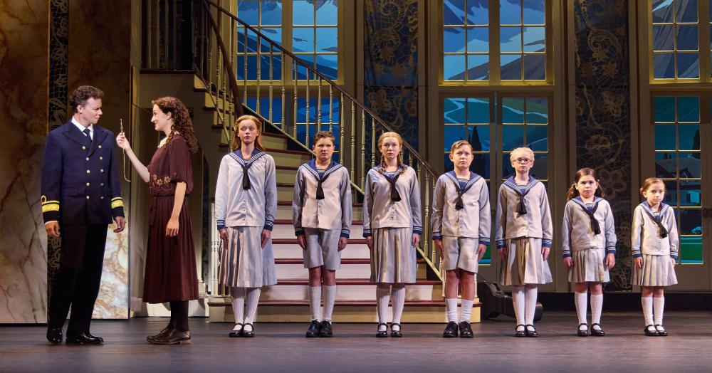 Kevin Earley (Captain Georg von Trapp) and Cayleigh Capaldi (Maria Rainer) with the von Trapp Children (l to r) Ariana Ferch (Liesl), Eli Vander Griend (Friedrich), Ava Davis (Louisa), Benjamin Stasiek (Kurt), Haddie Mac (Brigitta), Ruby Caramore (Marta), Luciana VanDette (Gretl) in The Sound of Music. Photo by Jeremy Daniel.