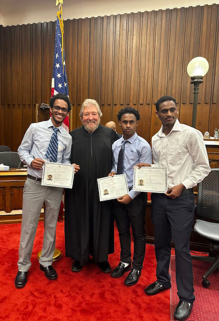 Tesfalem Mehari (left) and his brothers pose for a photo with Judge Rose following the naturalization ceremony